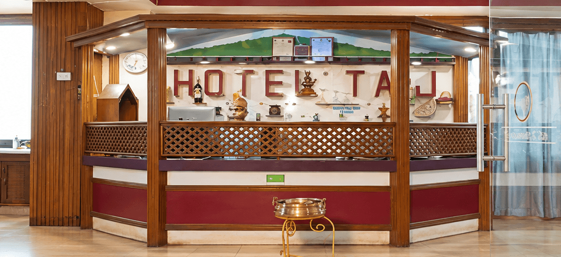 Hotel Taj reception lobby with a wooden welcome desk and burgundy detailing